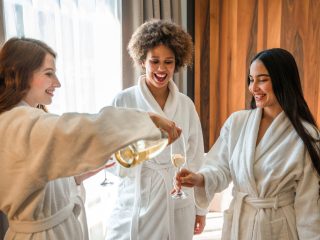 Diverse young women laughing, dancing and relaxing with a glass of sparkling wine.